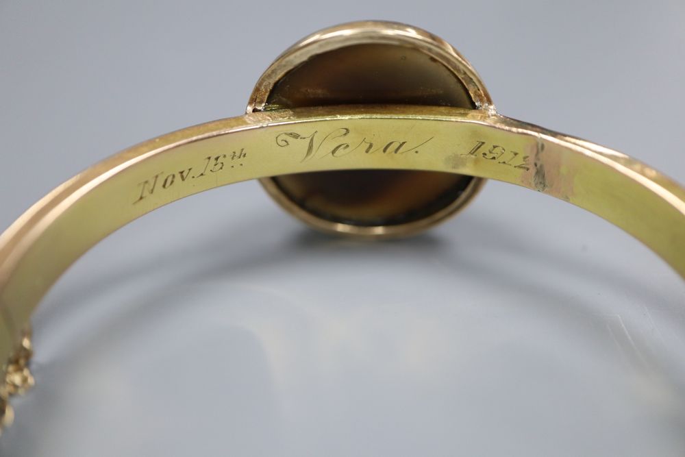 An early 20th century yellow metal (stamped 15) and banded agate set hinged bangle (repaired) and a Victorian mourning brooch.